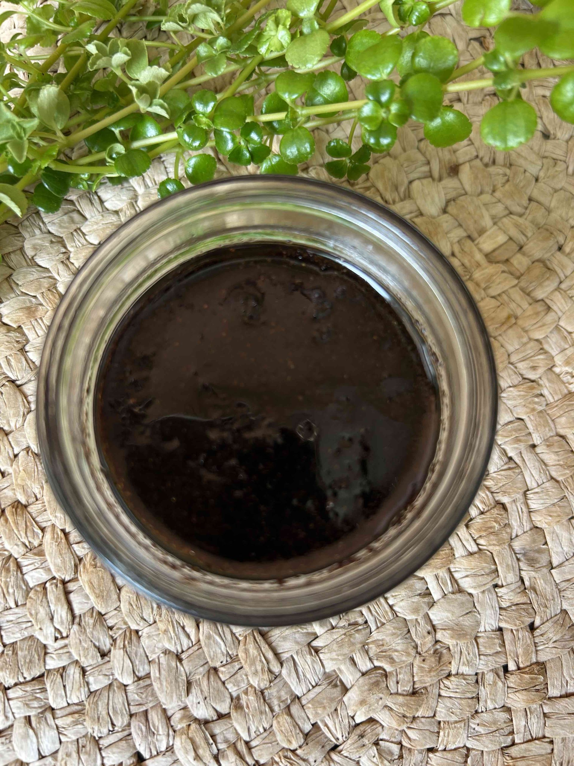 Recipiente de vidrio redondo con una mezcla exfoliante de café molido, azúcar, aceite de coco y aceite esencial de cúrcuma